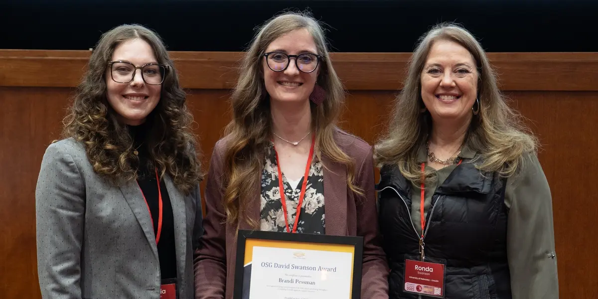 Photo Description: Brandi Pessman (center) receives the OSG David Swanson Award from Sophia (left) and Ronda Swanson (right). Credit: CHTC